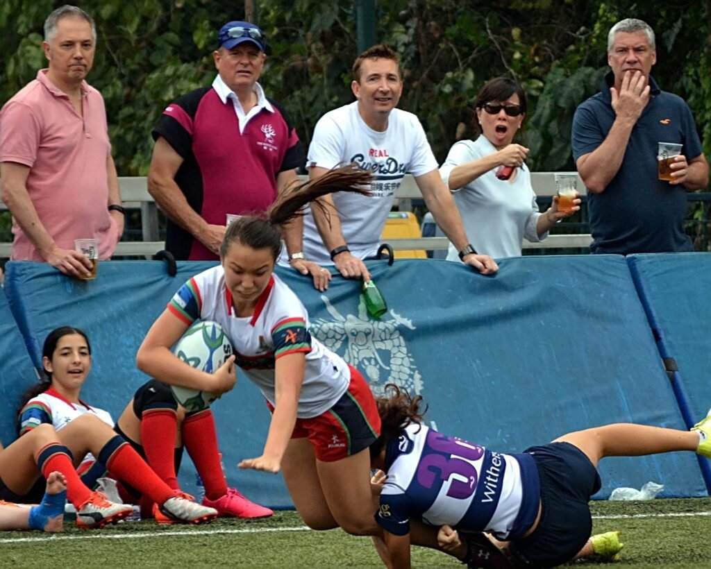 While parents look on, a girl is tackled at a rugby tournament in Hong Kong